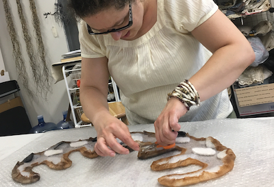 Sibel Adlai working around a uniquely designed template shape as well as applying the techniques of differential shrinkage and directional fulling to sculpt form. Eva Camacho Sanchez Studio workshop, North Hampton, Mass 2019.