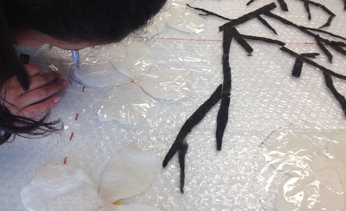 The second group in charge of the white leaves (what most think of us as the flowers, are actually a type of leaf with the yellow flowers in the center!) had the special task of laying a plastic resist over all but the center to keep the white leaves from attaching to the background